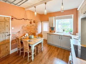 a kitchen with a table and a brick wall at Honey Cottage in Gargrave