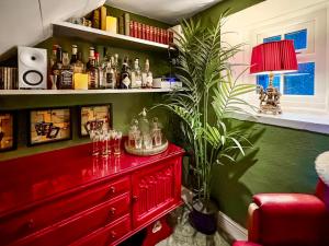 a red dresser in a green room with a plant at Honey Cottage in Gargrave