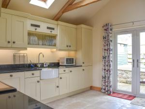 a kitchen with white cabinets and a sink and a window at Alpine Cottage in Carperby +11 photos