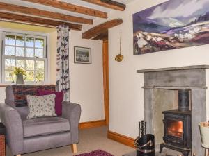 a living room with a chair and a fireplace at Alpine Cottage in Carperby