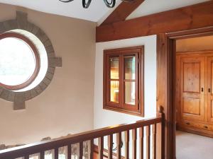 a staircase with a round window and a wooden door at Flatts Barn in Hebden