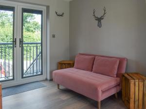 a living room with a pink couch and a balcony at Willows View in Etchingham