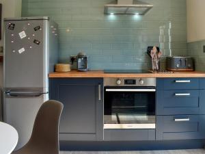 a kitchen with blue cabinets and a refrigerator at Willows View in Etchingham