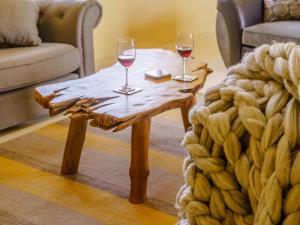 two glasses of wine on a wooden table in a living room at The Stables - Uk32514 in Marloes