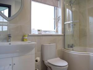 a bathroom with a toilet and a sink and a tub at Bumble Lodge in Llynclys