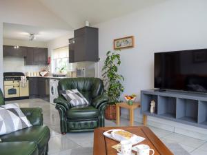 a living room with a green leather chair and a table at Bumble Lodge in Llynclys +4 photos