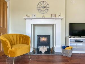 a living room with a yellow chair and a fireplace at Old School Mews Too in Shanklin
