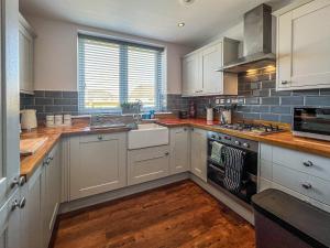 a kitchen with white cabinets and a sink and a stove at Old School Mews Too in Shanklin