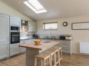 a kitchen with white cabinets and a wooden counter top at Oak Lodge in Hassocks