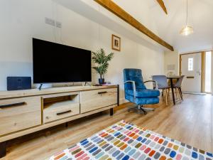 a living room with a flat screen tv on a dresser at Woodpecker Barn - Uk38613 in Wisbech