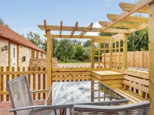 a wooden deck with chairs and a pergola at Woodpecker Barn - Uk38613 in Wisbech
