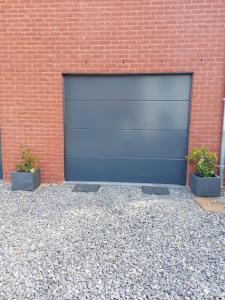 a blue garage door next to a brick building at Appartement meublé Tilff in Esneux