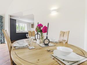 a dining room with a wooden table with plates and glasses at Kings Lodge in Neatishead