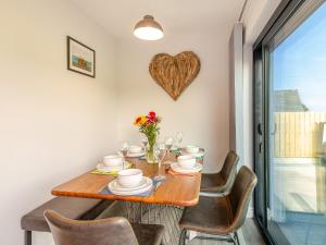 a dining room table with chairs and a heart decoration on the wall at Goppa in Llanfair