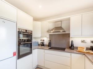 a white kitchen with white cabinets and appliances at Goppa in Llanfair +20 photos