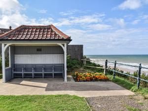 a gazebo with flowers in front of the beach at The Old Barn in Mundesley