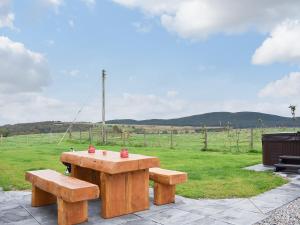 a picnic table and two benches in a field at 1 Dalbuaick Farm Cottage in Carrbridge