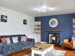 a living room with a couch and a fireplace at 1 Dalbuaick Farm Cottage in Carrbridge