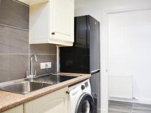 a kitchen with a sink and a refrigerator at 1 Dalbuaick Farm Cottage in Carrbridge
