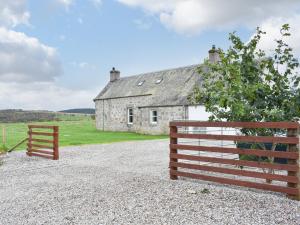 a barn and a fence in front of a house at 1 Dalbuaick Farm Cottage in Carrbridge +19 photos