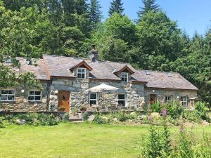 an old stone house with a garden in front of it at Clawdd Gwyn in Llanrwst