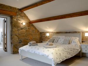 a bedroom with a bed in a stone wall at Clawdd Gwyn in Llanrwst