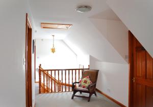 a chair in a hallway with a stair case at Auburn Cottage in Arbroath