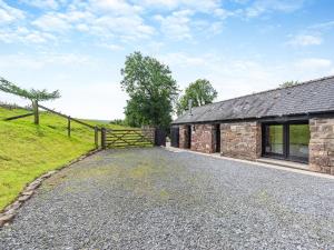 an external view of a stone barn with a wooden gate at Y Bwthyn-Oxm in Gwynfe