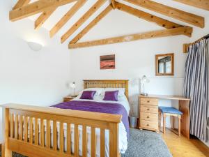 a bedroom with a wooden bed and a desk at Y Bwthyn-Oxm in Gwynfe