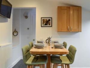 a dining room with a wooden table and green chairs at Logiemar Cottage in Ballater