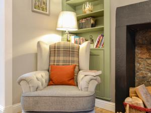 a chair with an orange pillow in a living room at Logiemar Cottage in Ballater