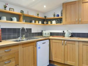 a kitchen with wooden cabinets and a white dishwasher at Logiemar Cottage in Ballater