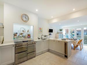 a kitchen with white cabinets and a dining room at Isfryn in Llanbedr