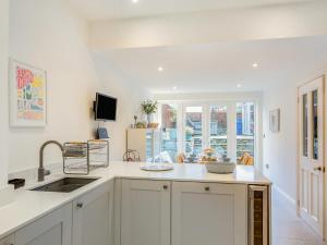 a kitchen with white cabinets and a sink and a window at Isfryn in Llanbedr