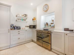 a kitchen with white cabinets and a mirror at Isfryn in Llanbedr