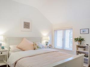 a white bedroom with a bed and a window at Isfryn in Llanbedr +19 photos