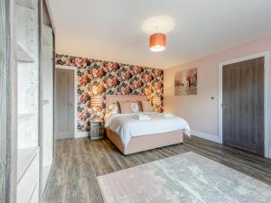 a bedroom with a bed and a floral wall at Cowslip Cottage - Uk47072 in Maltby le Marsh +18 photos