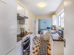 a kitchen with white cabinets and appliances and a bedroom at Spruce Cottage - Uk46875 in Hartland