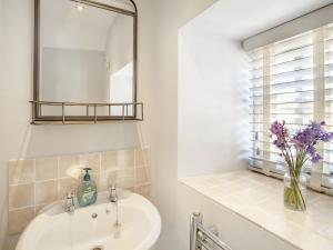 a bathroom with a sink and a mirror and a vase of flowers at Sandstones in Niton