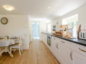 a kitchen with white cabinets and a table with a clock at The Chicken Coop in Fulletby +14 photos
