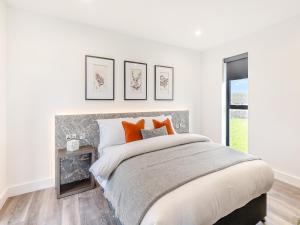 a white bedroom with a large bed with orange pillows at Seiriol Lodge 4 - Uk42794 in Llangefni