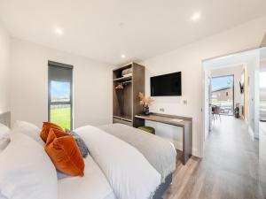 a white bedroom with a bed and a television at Seiriol Lodge 4 - Uk42794 in Llangefni