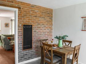 a dining room with a brick wall and a wooden table at No 8 Mouse Hole-Uk44302 in Sparham