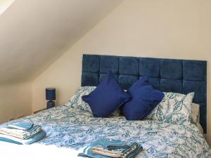 a bed with a blue headboard and blue pillows at No 8 Mouse Hole-Uk44302 in Sparham