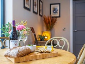 a table with a bottle of wine and a loaf of bread at The Granary - Uk48622 in Buchlyvie