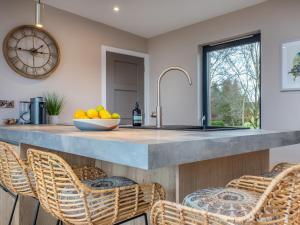 a kitchen with a counter with chairs and a clock at The Granary - Uk48622 in Buchlyvie +8 photos