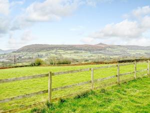 a fence in a field with hills in the background at Tyr Ywen Cottage in Abergavenny