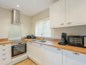 a kitchen with white cabinets and a sink at Tyr Ywen Cottage in Abergavenny