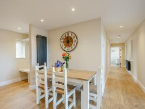 a dining room with a table and a clock on the wall at Tyr Ywen Cottage in Abergavenny +19 photos