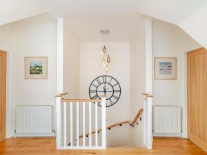a white staircase with a clock on the wall at Rose Cottage - Uk39245 in Inverness